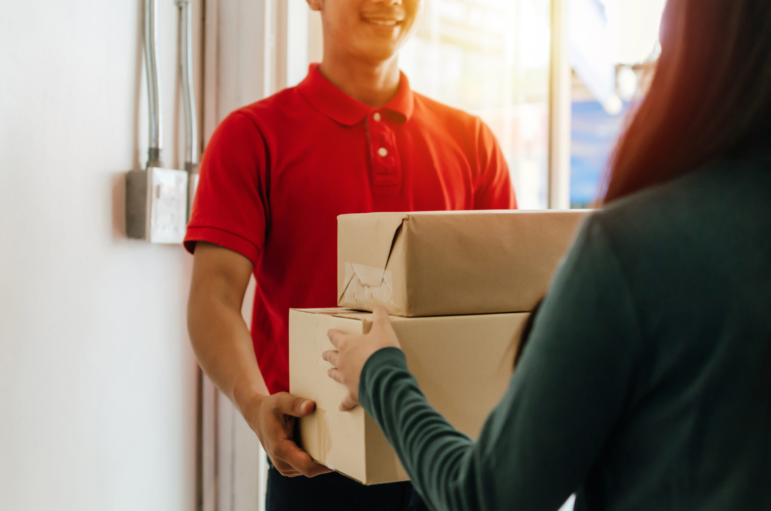 delivery service man in red uniform with young man customer receiving parcel post package box from courier at home, cargo shipping, express delivery service, online shopping and logistic concept